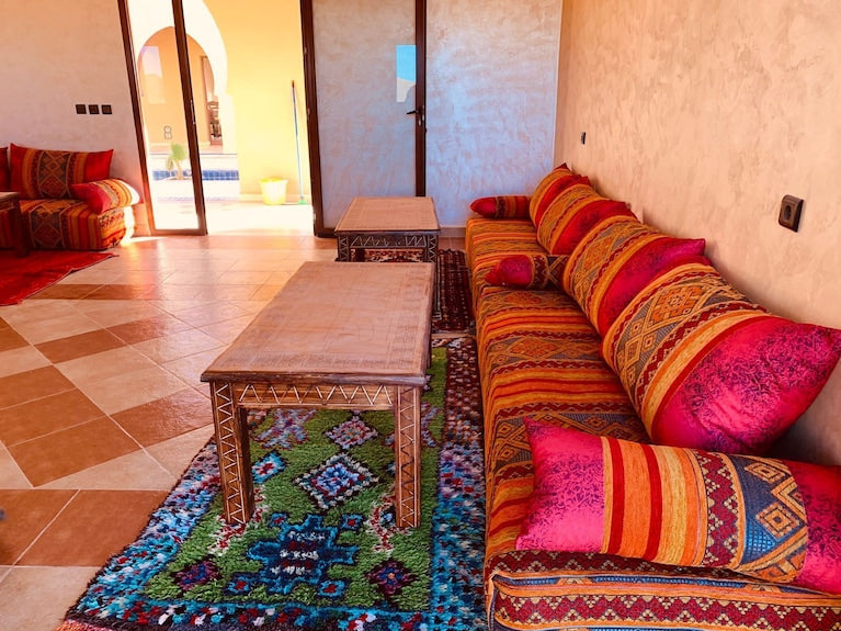 Berber Palace Hotel vibrant red and orange patterned sofa with matching cushions on colorful geometric rug beside wooden tables