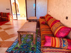 Berber Palace Hotel vibrant red and orange patterned sofa with matching cushions on colorful geometric rug beside wooden tables