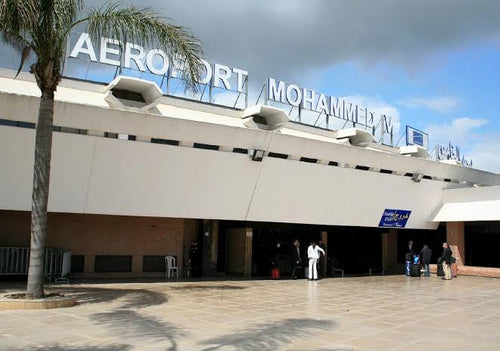 airport terminal building exterior in Morocco with white walls and Aeroport Mohammed V sign under cloudy sky for Book Flight Tickets