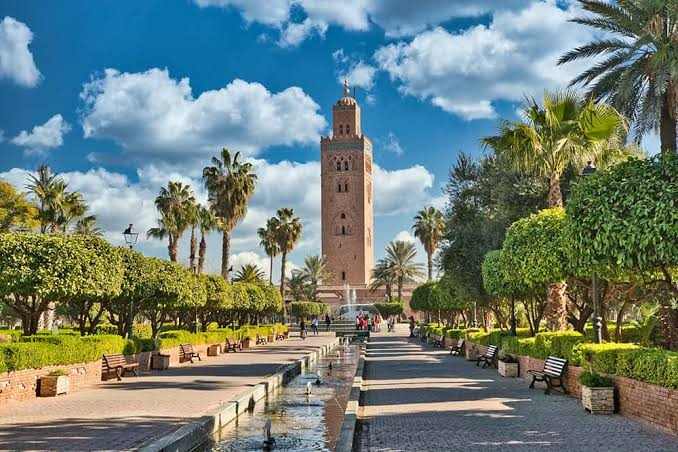 Booking Flight Tickets shows a view of Marrakech with the Koutoubia Mosque surrounded by palm trees and a water feature under blue sky