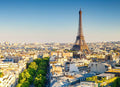 Bright cityscape of Paris with the Eiffel Tower prominently standing above beige buildings and green tree-lined streets, ideal for Booking Flight Tickets