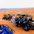 Off-road black and blue all-terrain buggies lined up on orange desert sand with two people wearing helmets, showcasing Buggy Rental in Merzouga.