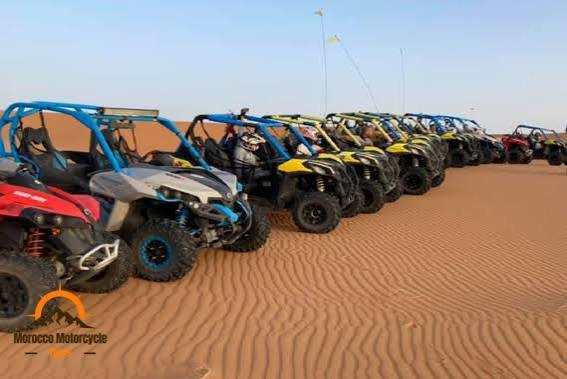 Lineup of off-road buggies in various colours including blue, yellow, and red, parked on rippled desert sand for Buggy Rental in Merzouga.