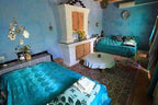 Traditional Moroccan bedroom with turquoise bedspreads, blue painted walls, patterned rugs, and decorative ceramic tiles, ideal for Camel Trekking in the Sahara Desert.