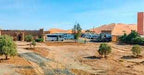 Camping La Gazelle Bleue features white desert tents with blue trim, set on sandy terrain near orange sand dunes and sparse greenery.
