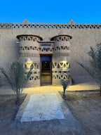 Camping La Gazelle Bleue entrance featuring traditional Moroccan mud architecture with decorative geometric patterns and blue signage at dusk