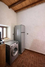 Casa Mona apartment kitchen area with silver washing machine and refrigerator, white textured walls, and wooden ceiling beams
