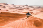 SUV in white navigating golden sand dunes under a clear sky, showcasing adventure in the desert landscape for Day Tour from Erfoud to Merzouga.
