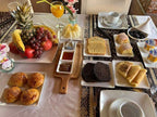 Breakfast spread featuring fresh fruits, pastries, honey, jam, yogurt, and tea set on a patterned tablecloth for a Desert Trip to Merzouga