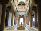 Desert Villa Boutique Hotel interior showing beige columns and arches with intricate blue mosaic tilework above a central reflective water fountain