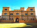Desert Villa Boutique Hotel in beige stucco with traditional Moroccan architectural details and green tile accents under a clear blue sky