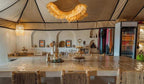 Dihya Desert Camp interior with beige tiled counter, wicker chairs, rustic decor, and hanging woven lampshades