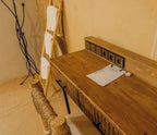 Dihya Desert Camp wooden desk with built-in power sockets and rustic woven chair in warm beige interior