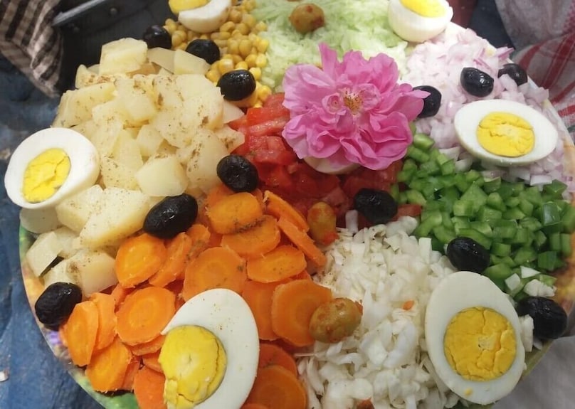 Erg Chigaga Star Camp colorful mixed vegetable salad with boiled eggs, black olives, and a pink flower garnish