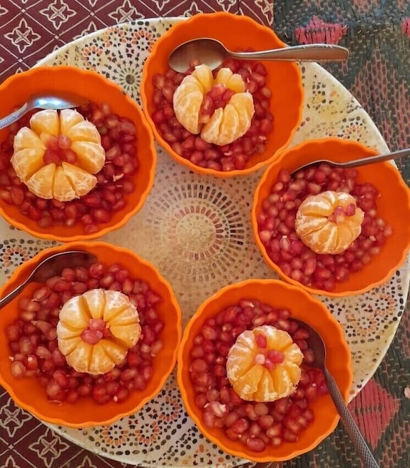 Erg Chigaga Star Camp small orange bowls filled with pomegranate seeds topped with peeled mandarin slices arranged on decorative mosaic plate