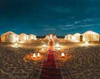 Errachidia Airport luxury desert tents in beige with warm lighting and red carpet pathway in sandy Sahara desert at night