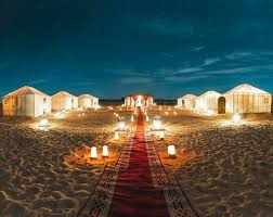 Errachidia Airport luxury desert tents in beige with warm lighting and red carpet pathway in sandy Sahara desert at night