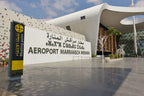 Airport exterior of white and glass Aeropot Marrakech Menara with geometric patterns and a yellow Meeting Point sign visible
