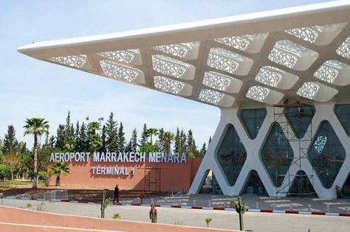 Modern outdoor view of Marrakech Menara Airport Terminal 1 with white geometric canopy and glass facade under clear sky