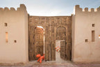Four Seasons Resort Marrakech traditional large carved wooden gates with intricate Moroccan designs and beige stucco walls