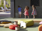 Children drawing on a black outdoor chalkboard wall at Four Seasons Resort Marrakech with colorful cushions and toys on green ground