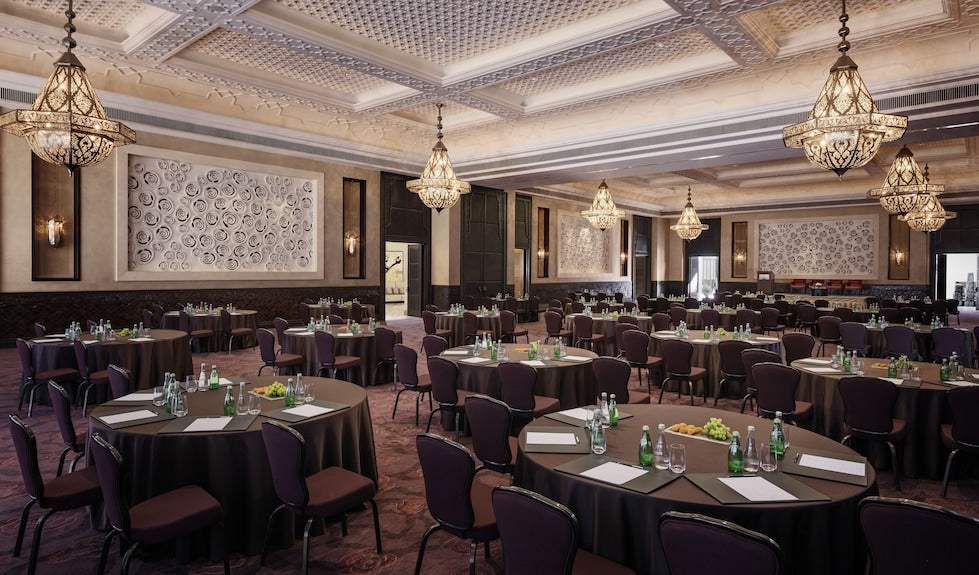 Four Seasons Resort Marrakech elegant conference room with round tables, purple chairs, black linens, and ornate chandeliers