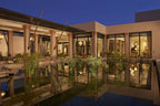 Four Seasons Resort Marrakech exterior view at dusk featuring Moroccan-inspired architecture with columns and reflective water garden