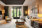 Four Seasons Resort Marrakech living room with beige sectional sofa, patterned cushions, glass coffee table, wooden side table, olive green armchair, and large glass doors