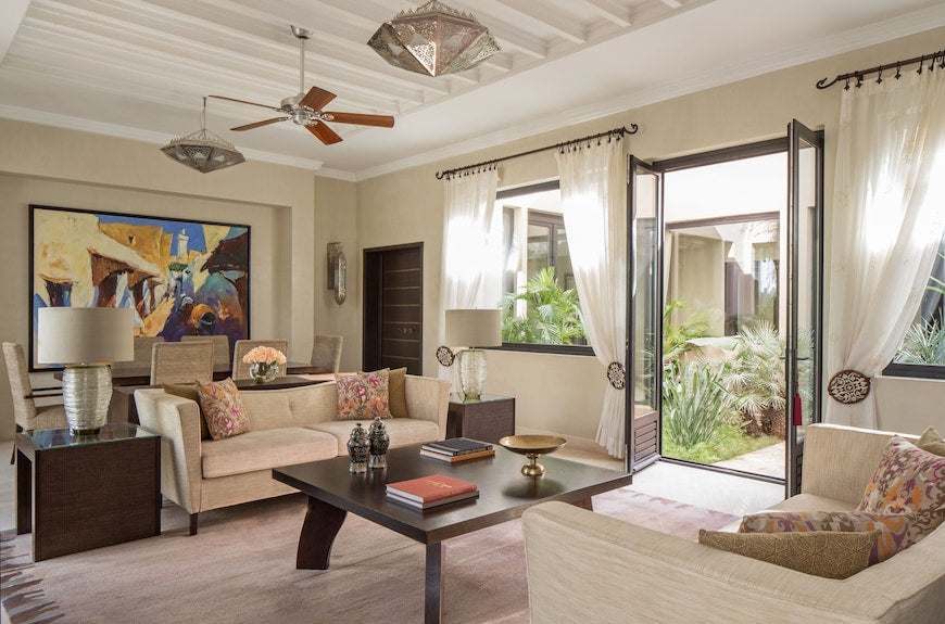 Four Seasons Resort Marrakech living room with beige sofas, dark wood coffee table, colorful cushions, and bright natural light