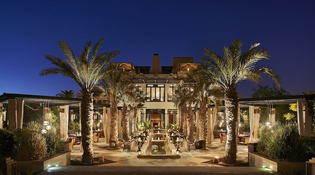 Four Seasons Resort Marrakech luxurious outdoor dining area with palm trees, elegant seating, and ambient nighttime lighting