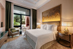 Four Seasons Resort Marrakech room featuring a large bed with white linens, wooden nightstands, ambient lighting, and a seating area with beige and green accents