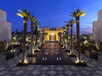 Four Seasons Resort Marrakech luxury hotel at dusk with illuminated palm trees, water fountains, and Moroccan-inspired architecture