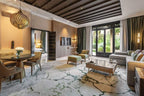 Four Seasons Resort Marrakech living room with beige and green tones, wooden accents, stylish furniture, large glass doors opening to garden view