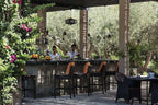 Four Seasons Resort Marrakech outdoor bar area with stone countertop, black chairs, green plants, and shaded patio