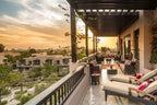 Four Seasons Resort Marrakech outdoor terrace with beige cushioned chairs, dark wooden pergola, decorative plants, and sunset view