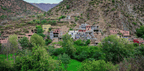 From Marrakech to Ourika Valley tour showing colourful mountain village homes among green trees and rocky Atlas slopes