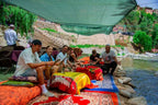From Marrakech to Ourika Valley tour with people relaxing beside a river on colourful Moroccan rugs