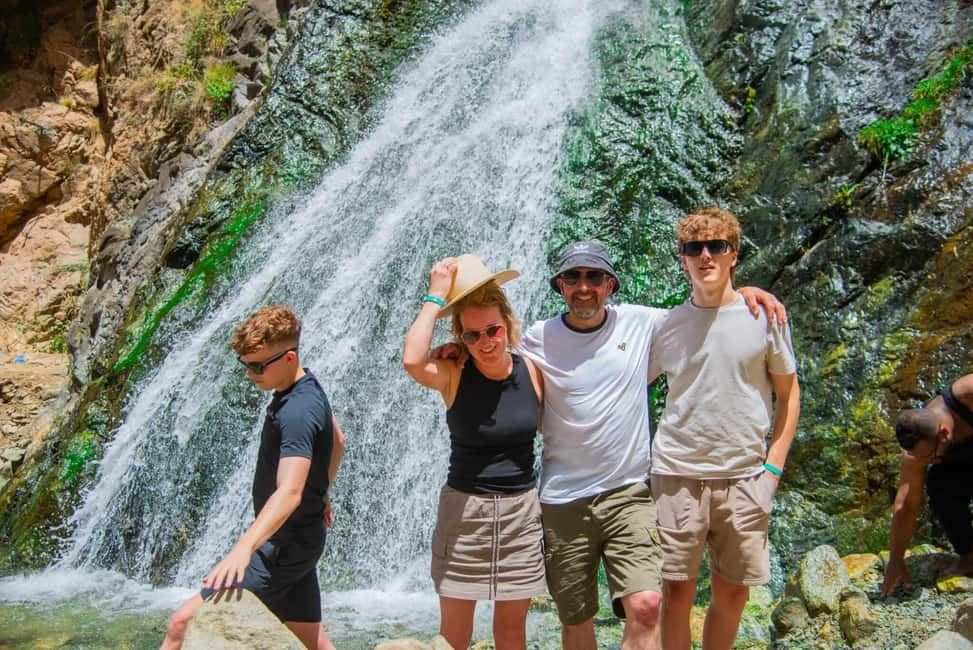 From Marrakech to Ourika Valley tour group posing beside a cascading waterfall in the Atlas Mountains