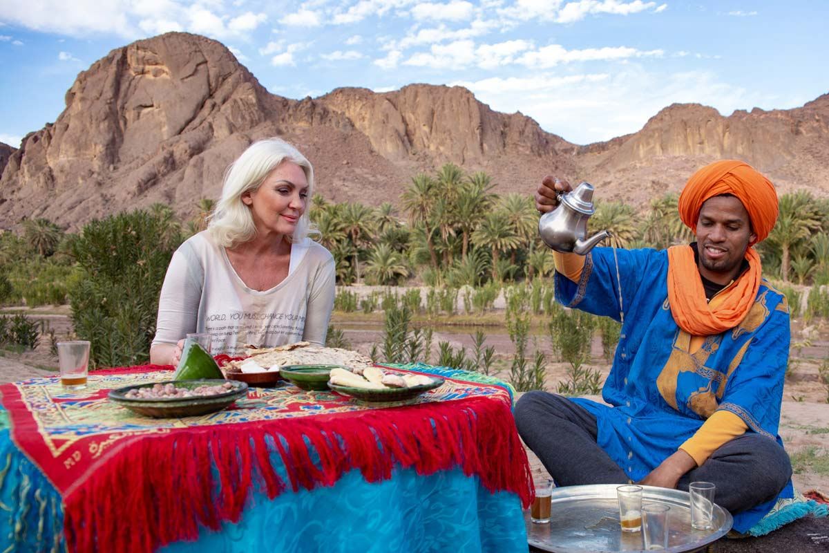 From Marrakech: To Sahara Tour featuring Moroccan tea served at a colourful table beside a palm oasis