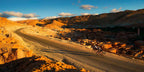 From Marrakech: To Sahara Tour showing a winding mountain road, ochre village, and two cyclists in Morocco