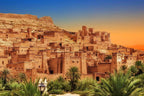 From Marrakech: To Sahara Tour featuring a warm ochre Moroccan kasbah village with palm trees and fortified towers
