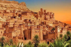 Ancient earthen kasbah with multiple terraced levels and traditional Moroccan architecture at sunset, featured in Group Tours from Marrakech.