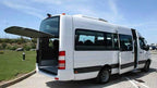 White passenger minibus with black tinted windows and an open rear door parked on a paved area, suitable for Group Tours from Marrakech.