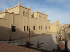 Hassilabiad Appart Hotel beige stucco buildings with traditional architectural details and small landscaped garden