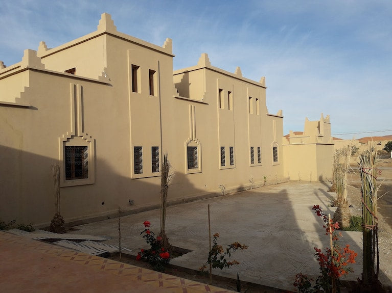 Hassilabiad Appart Hotel beige stucco buildings with traditional architectural details and small landscaped garden