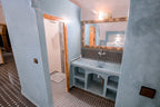 Bathroom with blue plastered walls, patterned brown and white floor tiles, wooden door frame, and a mirror above the sink at Hassilabiad Appart Hotel