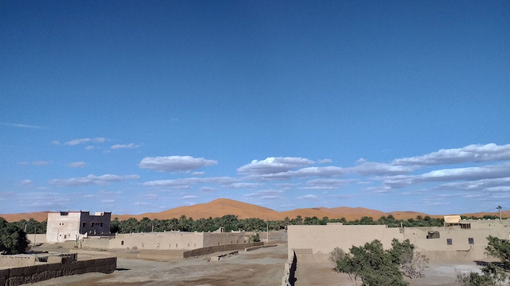 Hassilabiad Appart Hotel beige desert buildings with flat roofs surrounded by trees under blue sky