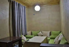 Living area with green and beige cushioned sofa set, beige walls, gold textured ceiling, and a round pendant light in Hassilabiad Appart Hotel
