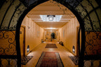 Hassilabiad Appart Hotel hallway with warm orange walls, patterned rugs, decorative iron archway, and ceiling light fixtures