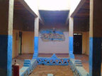 Hostel Dar Lgamra courtyard with blue and beige painted walls and decorative mural in Merzouga